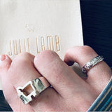 Signature lamb logo rings shown worn on finger