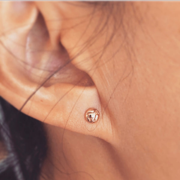 Lam logo stud earrings shown on ear in 14K rose gold